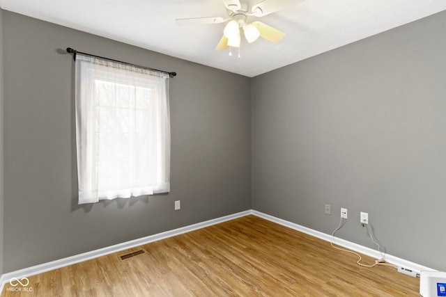 spare room featuring visible vents, ceiling fan, baseboards, and wood finished floors