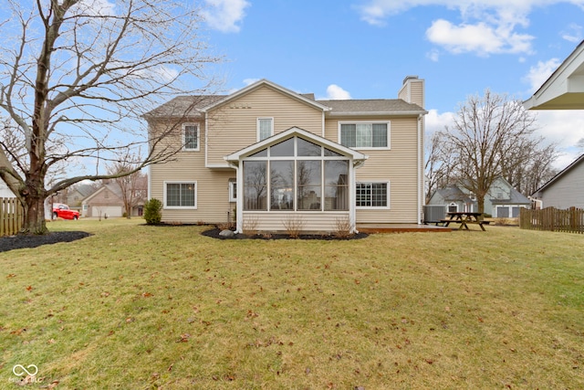 back of house with a sunroom, fence, a chimney, and a lawn