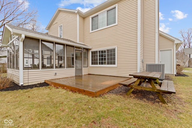 rear view of property featuring a sunroom, cooling unit, a lawn, and a wooden deck