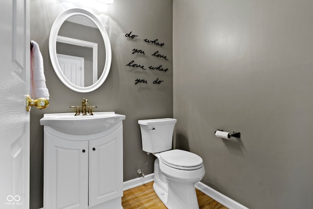 bathroom featuring baseboards, vanity, toilet, and wood finished floors