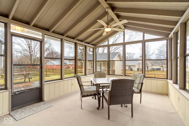 sunroom featuring lofted ceiling with beams, ceiling fan, and a residential view