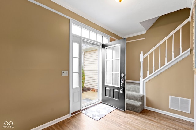 entrance foyer featuring wood finished floors, visible vents, baseboards, stairs, and crown molding