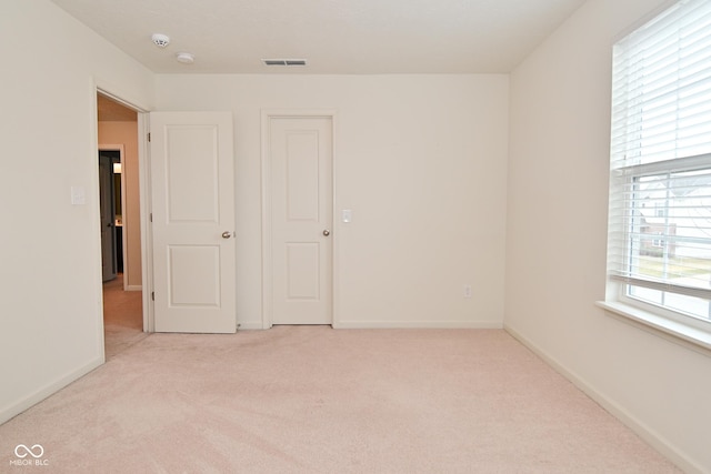 unfurnished room with baseboards, visible vents, and light colored carpet