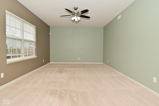 spare room featuring ceiling fan, baseboards, visible vents, and light colored carpet