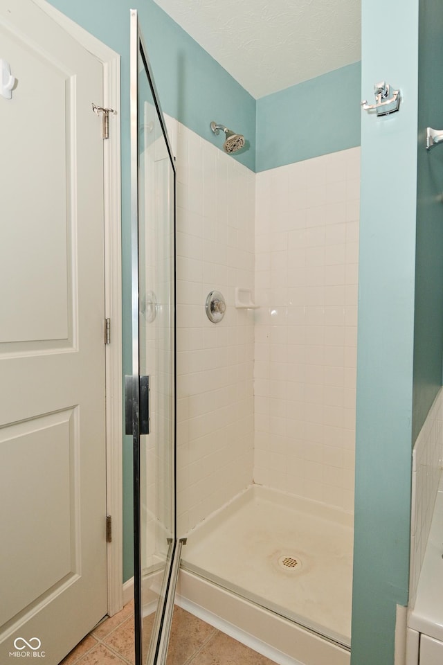 bathroom with a shower stall and tile patterned floors