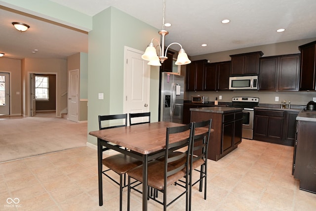 kitchen with dark countertops, a kitchen island, appliances with stainless steel finishes, dark brown cabinets, and recessed lighting