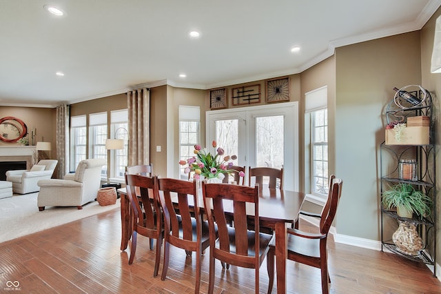 dining area with a fireplace, crown molding, baseboards, and wood finished floors