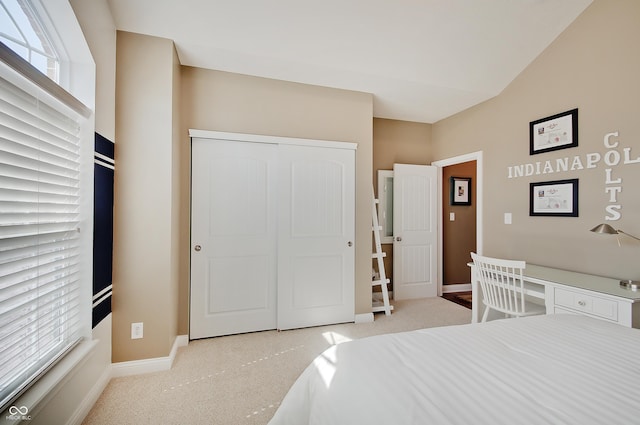 bedroom with lofted ceiling, carpet, baseboards, and a closet