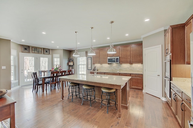 kitchen featuring backsplash, a breakfast bar area, ornamental molding, stainless steel appliances, and a sink