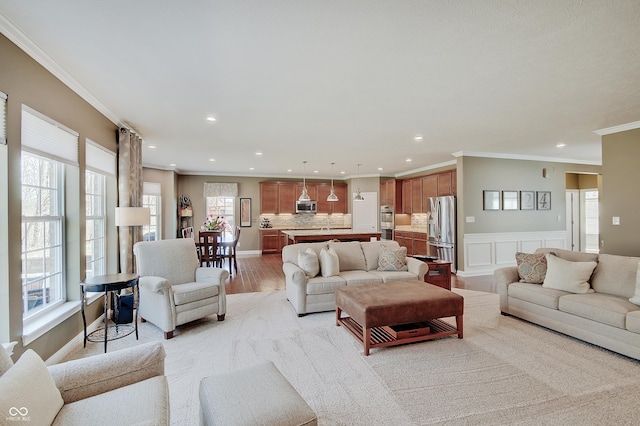 living area featuring light wood finished floors, recessed lighting, wainscoting, a decorative wall, and crown molding