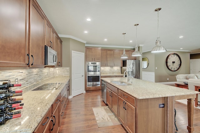 kitchen featuring a breakfast bar, a sink, appliances with stainless steel finishes, crown molding, and light wood-type flooring