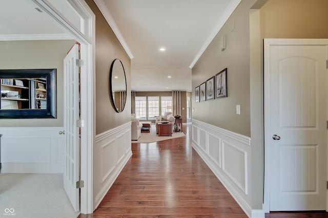 hall with a wainscoted wall, ornamental molding, wood finished floors, recessed lighting, and a decorative wall