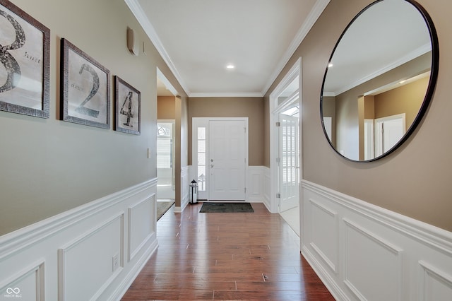 foyer entrance with a decorative wall, wainscoting, dark wood-style flooring, and ornamental molding