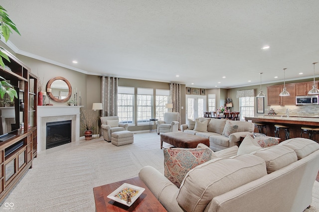 living room with light colored carpet, ornamental molding, a fireplace, and a textured ceiling