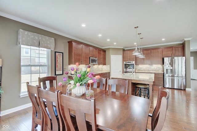 dining room with light wood-type flooring and crown molding