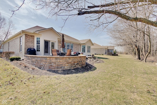 back of house with brick siding, a yard, and a patio