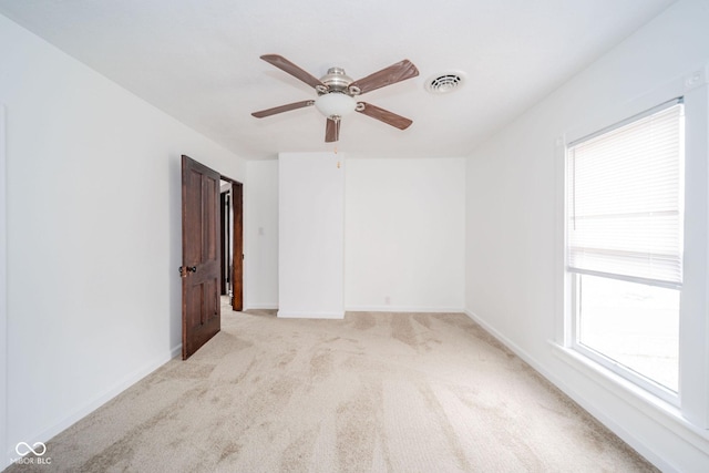 spare room with light carpet, baseboards, visible vents, and ceiling fan