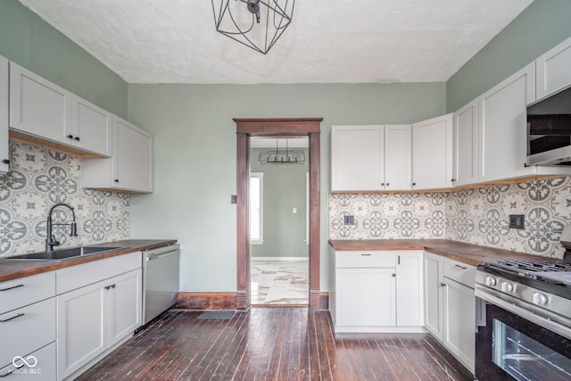 kitchen featuring dark wood-style flooring, wooden counters, appliances with stainless steel finishes, white cabinetry, and a sink