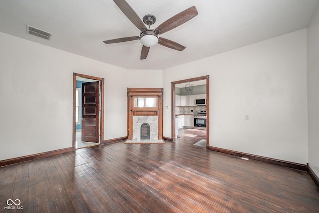 unfurnished living room featuring wood-type flooring, a premium fireplace, visible vents, and baseboards