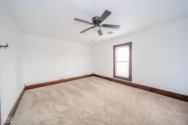 spare room with carpet floors, ceiling fan, visible vents, and baseboards