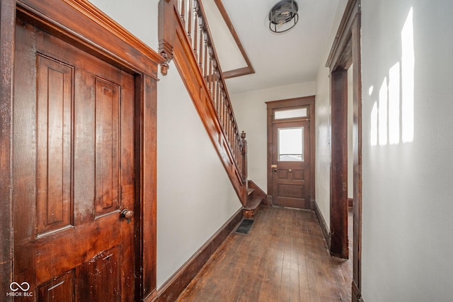 entryway with stairway, dark wood finished floors, visible vents, and baseboards