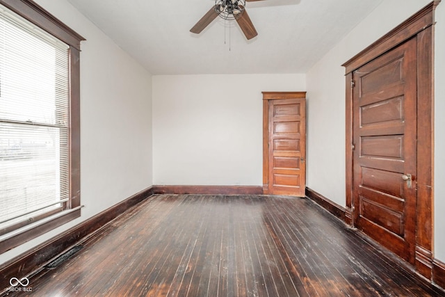 empty room with a healthy amount of sunlight, wood-type flooring, a ceiling fan, and baseboards