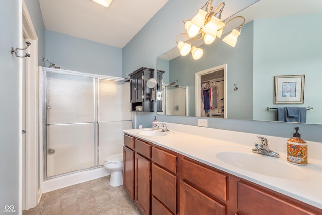 bathroom with double vanity, a stall shower, a notable chandelier, and a sink