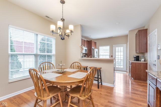 dining space with light wood-type flooring, visible vents, a notable chandelier, and baseboards