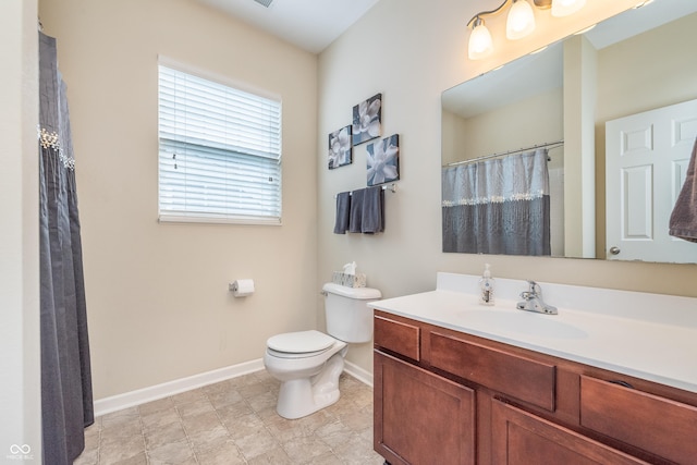 bathroom with baseboards, vanity, and toilet