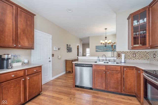 kitchen with light countertops, light wood-style flooring, appliances with stainless steel finishes, a sink, and a peninsula