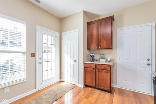 doorway to outside featuring light wood-style flooring, a wealth of natural light, and baseboards