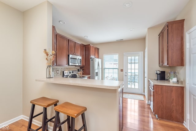 kitchen with appliances with stainless steel finishes, light countertops, and brown cabinetry