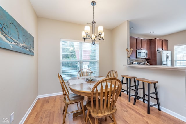 dining area featuring a notable chandelier, light wood-style flooring, and baseboards