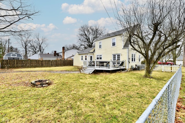 back of property featuring a fenced backyard, a lawn, a fire pit, and a wooden deck