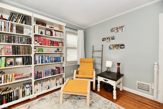 sitting room featuring baseboards, crown molding, visible vents, and wood finished floors