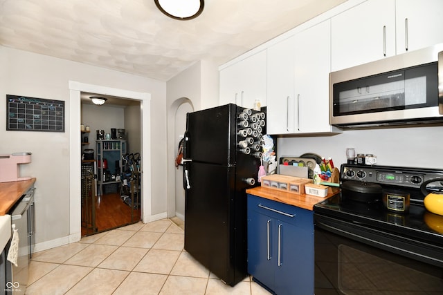 kitchen with blue cabinetry, white cabinetry, light tile patterned flooring, butcher block countertops, and black appliances