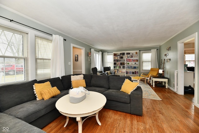 living area featuring baseboards, wood finished floors, and crown molding