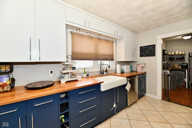 kitchen with a sink, blue cabinets, wooden counters, and stainless steel dishwasher