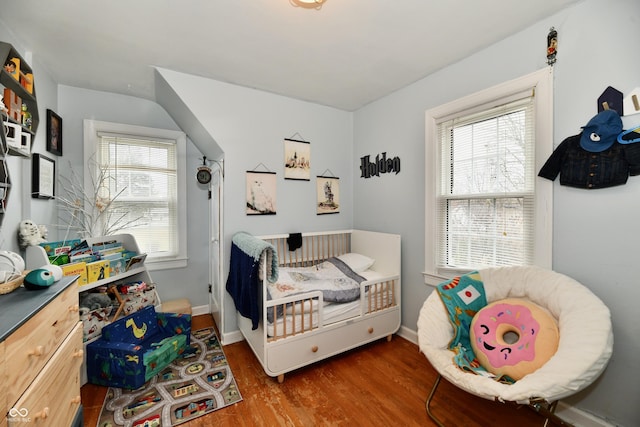 bedroom featuring multiple windows, baseboards, and wood finished floors