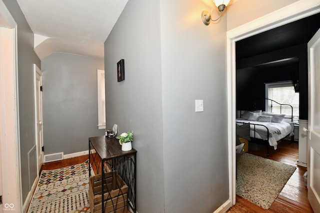 corridor featuring visible vents, baseboards, and wood finished floors