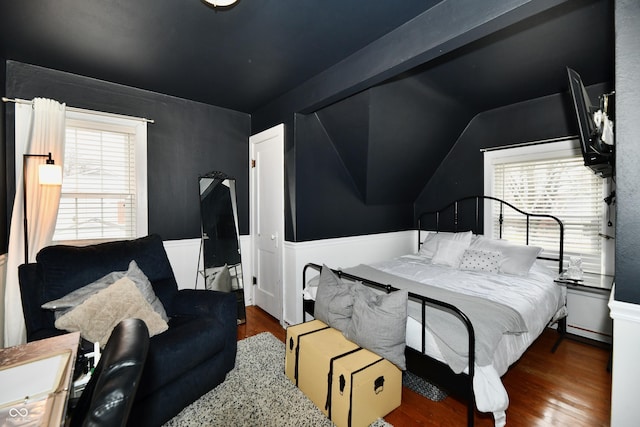 bedroom with multiple windows, vaulted ceiling, and wood finished floors