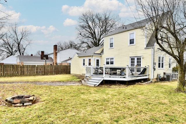 rear view of property with a deck, a fire pit, central AC, fence, and a lawn