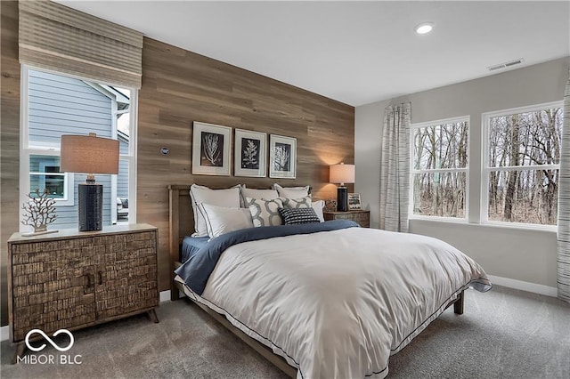 bedroom with wood walls, carpet flooring, visible vents, and baseboards