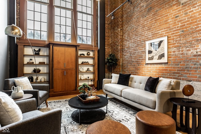 living area featuring brick wall and a high ceiling