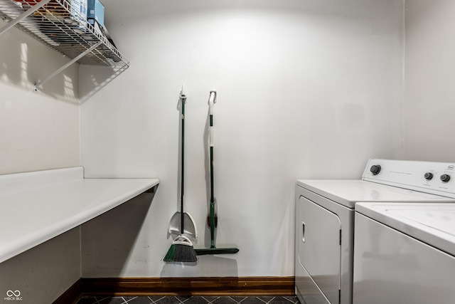 washroom featuring laundry area, dark tile patterned floors, washing machine and clothes dryer, and baseboards