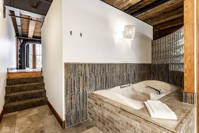 bathroom with a garden tub and baseboards