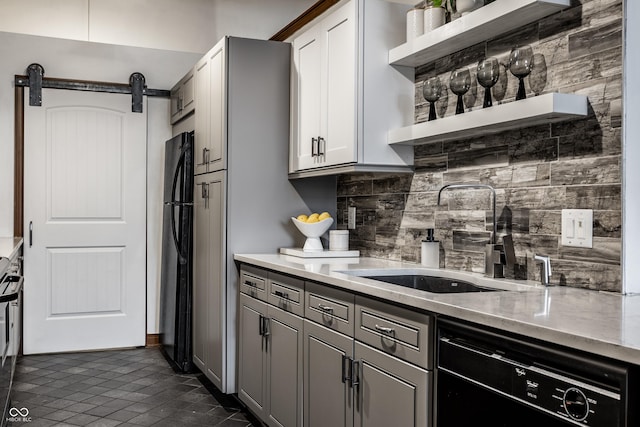 kitchen with a barn door, open shelves, a sink, decorative backsplash, and black appliances