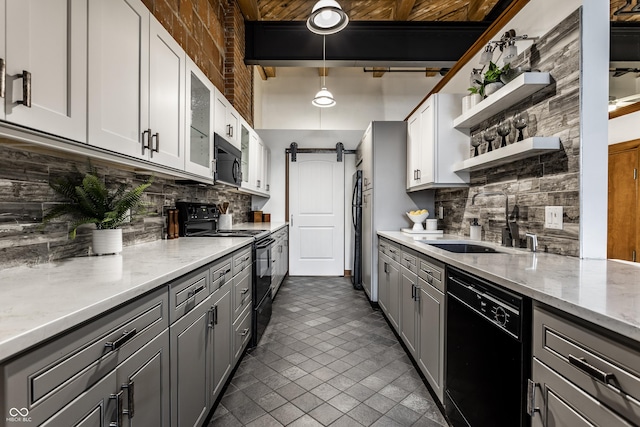 kitchen with a barn door, open shelves, a sink, gray cabinets, and black appliances