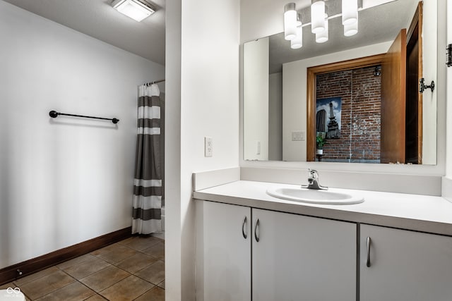 bathroom with a shower with shower curtain, a textured ceiling, vanity, baseboards, and tile patterned floors