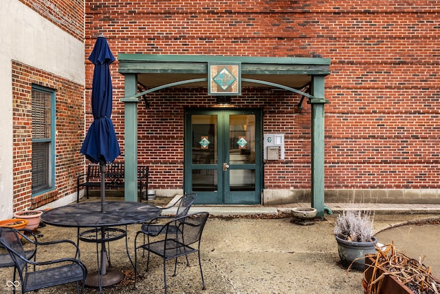 property entrance with brick siding, outdoor dining space, a patio area, and french doors